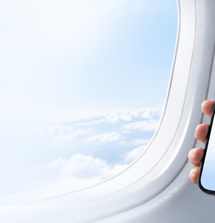 Traveler holding a smartphone beside an airplane window